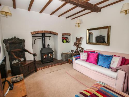 sala de estar con sofá y estufa de leña en Lower Woodend Cottage, en Ludlow