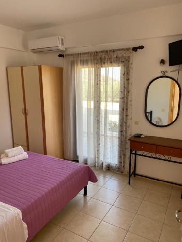 a bedroom with a purple bed and a mirror at Rousolakos Apartments in Palekastron