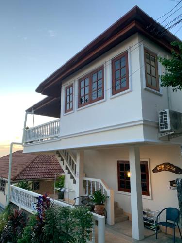 a white house with a porch and a balcony at Scan House Apartment in Karon Beach
