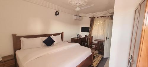 1 dormitorio con cama blanca y ventana en Downtown Virgins Hotel, en Elmina
