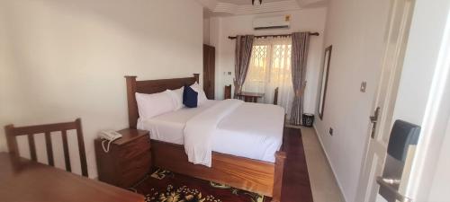 a bedroom with a bed with white sheets and a phone at Downtown Virgins Hotel in Elmina