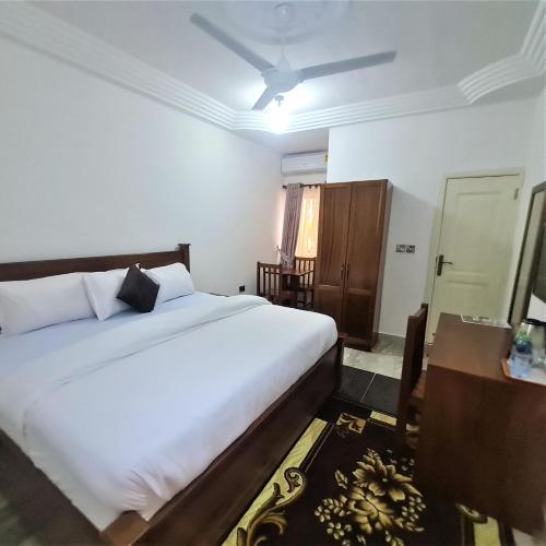 a bedroom with a large white bed and a table at Downtown Virgins Hotel in Elmina
