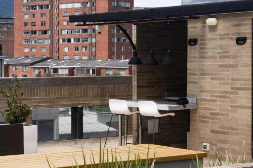 a table and two white chairs on a balcony at Apartahotel Connect Bogotá in Bogotá