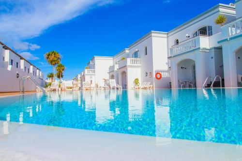 a large swimming pool with blue water in front of buildings at Apartamentos Corona Mar in Puerto del Carmen
