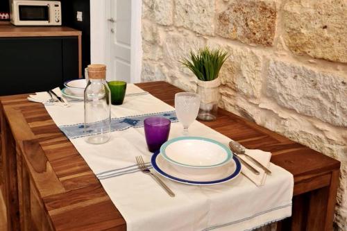 a table with plates and silverware on a white table cloth at BassaMarea - Una sorpresa in Centro storico in Carloforte
