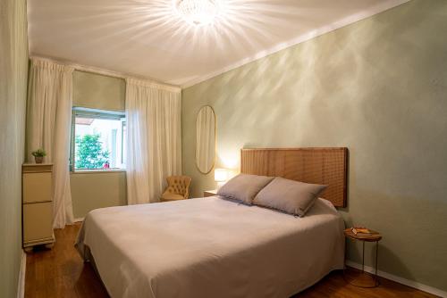 um quarto com uma grande cama branca e uma janela em Apartamento Fortaleza em Sesimbra
