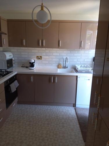 a kitchen with brown cabinets and a white appliance at Hill's View in Barnstaple