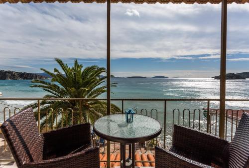 a patio with a table and chairs and the ocean at Hotel Assini Beach Tolo in Tolo