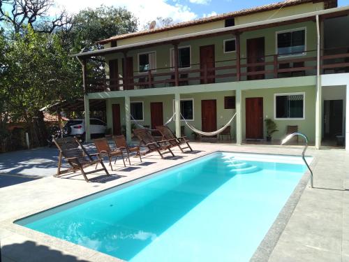 une piscine avec des chaises et un bâtiment en face d'un hôtel dans l'établissement Estadia cipó, à La Serra do Cipo