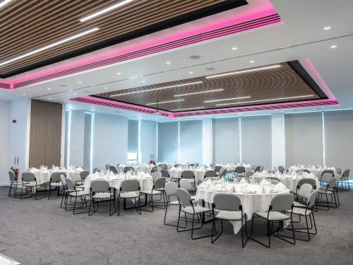 a banquet hall with white tables and chairs at Holiday Inn Birmingham Airport - NEC by IHG in Bickenhill