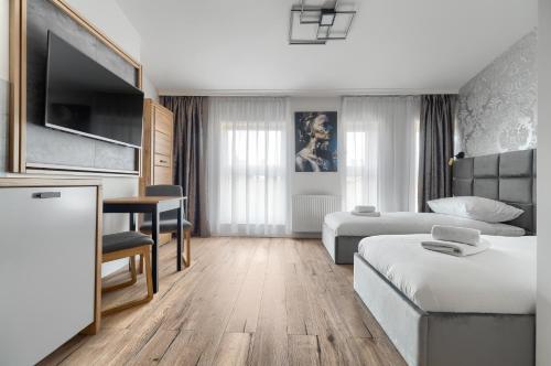 a hotel room with a bed and a desk and a bed and a couch at Toress Apartamenty plac Grunwaldzki in Szczecin