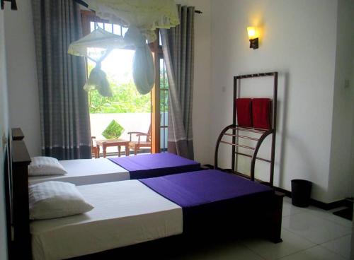a bedroom with a large bed and a window at Surf'n Lanka - Surf School in Weligama