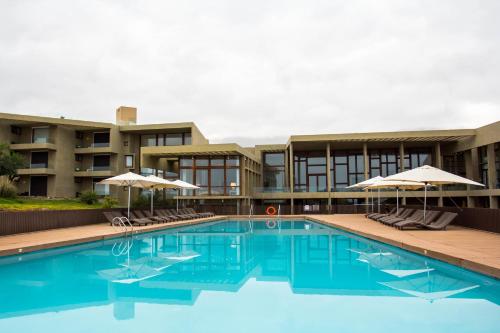 Una piscina con sillas y sombrillas frente a un edificio. en Hotel y Cabañas Hornitos - Caja Los Andes, en Hornitos