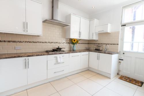 a white kitchen with white cabinets and a window at Superb 4 BR Home in Leicester near Bus Stops in Leicester