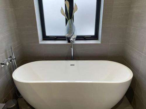a white bath tub in a bathroom with a window at Couples Canalside Retreat with Hot Tub & Pergola in Poynton