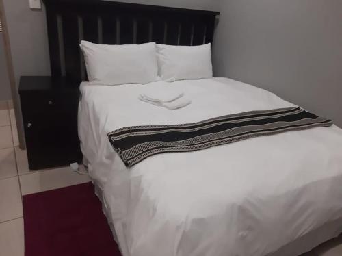 a bed with a black and white blanket on it at Sis-V's Inn in East London