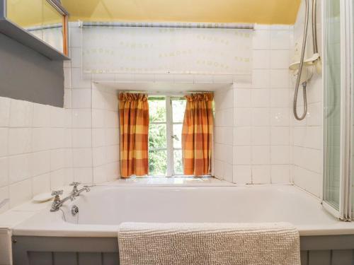 a bath tub in a bathroom with a window at Woodbine Cottage in Moreton in Marsh