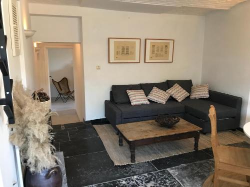 a living room with a black couch and a table at Maison de charme à Crupet et le gîte la suite in Crupet