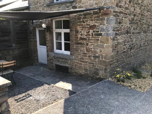 a stone house with a white door and an umbrella at Maison de charme à Crupet et le gîte la suite in Crupet