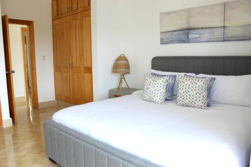 a bedroom with a large white bed with blue pillows at Amar'e Aparthotel & Spa in Las Terrenas