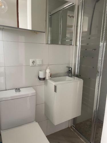 a white bathroom with a toilet and a sink at Beach-Goretti House in Mairena del Aljarafe
