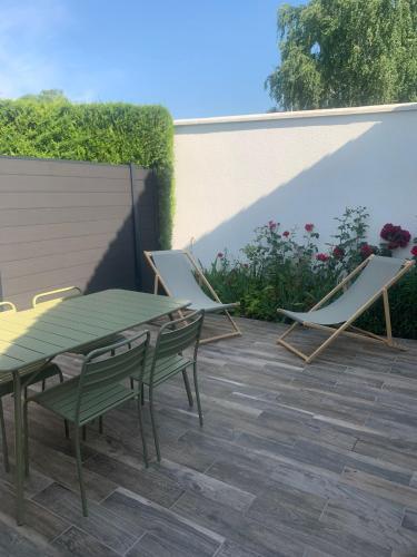 a patio with two chairs and a green table and chairs at Maison des Larris in Beauvais