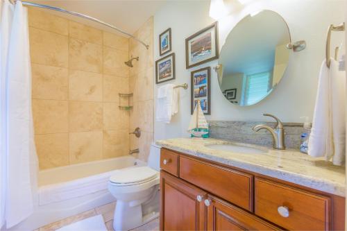 een badkamer met een wastafel, een toilet en een spiegel bij 2 Bedroom Kapaa Condo with Pool and AC 115 in Kapaa