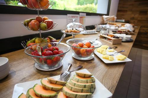 une table avec des bols de fruits et des assiettes de nourriture dans l'établissement Hotel Bellavista Locarno, à Locarno