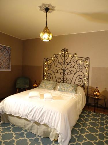 1 dormitorio con 1 cama blanca grande con lámpara de araña en DÉDÉ DU VAL B&B, en Florac