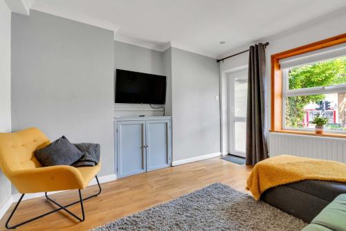 a living room with a television and a chair at The Retreat on Risbygate in Bury Saint Edmunds