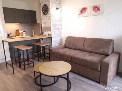 Il comprend un salon avec un canapé et des tables ainsi qu'une cuisine. dans l'établissement Escapade en bord de mer : studio à la plage !, à Courseulles-sur-Mer