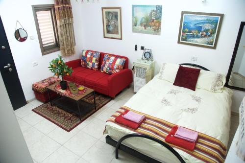 a bedroom with a bed and a red couch at Country House in Beer Sheva