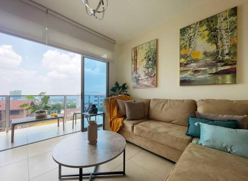 Una sala de estar con un sofá y una mesa y una ventana grande. en Encanto Urbano, en San Salvador