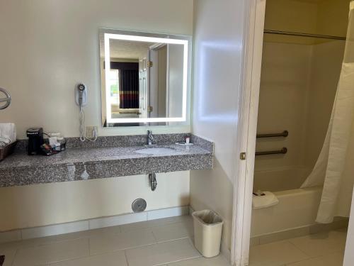 a bathroom with a sink and a mirror and a tub at Surry Inn - Dobson in Dobson