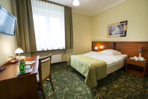 a hotel room with a bed and a desk at Brojan in Jaworzno