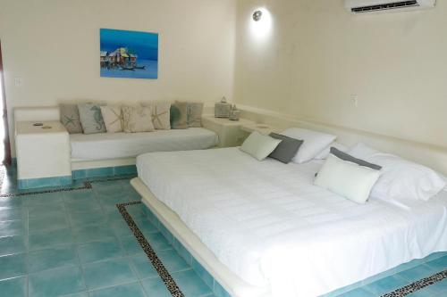 a bedroom with a large white bed and a couch at Tintipan Cabana SalSiPuedes in Tintipan Island