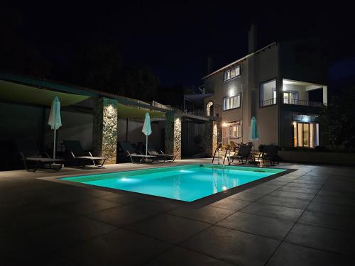 a swimming pool in front of a house at night at Ionian Juliet Villas in Kothoníkion