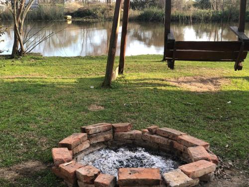 a brick fire pit in the grass near a body of water at La griself in Morón