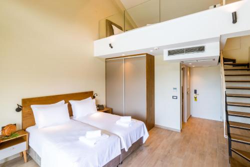a bedroom with a white bed and a staircase at EPHYRA in Sivota