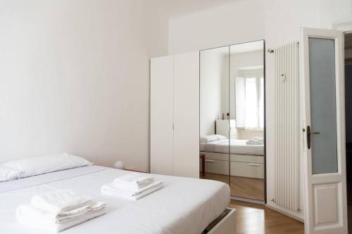 ein weißes Schlafzimmer mit einem Bett und einem Spiegel in der Unterkunft YouHosty - Correggio 55 B in Mailand