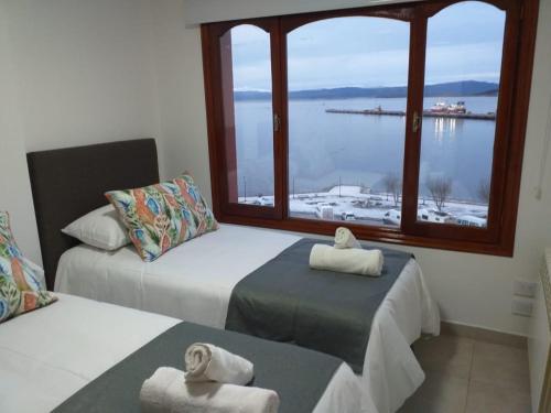 2 Betten in einem Zimmer mit einem großen Fenster in der Unterkunft Mirando al Sur in Ushuaia