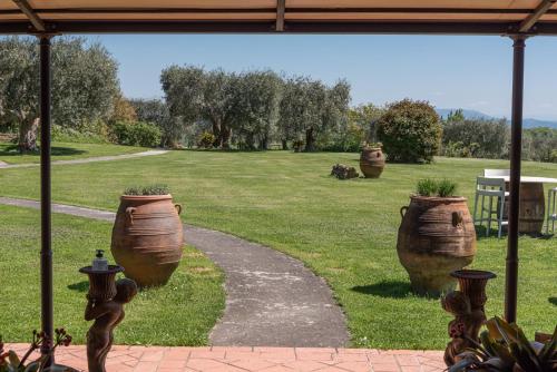 a garden with three large vases on the grass at Locanda Poggioleone in Castiglione del Lago