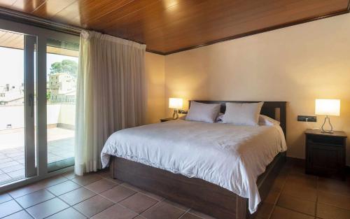 a bedroom with a large bed and a balcony at Luxury Rocamar Primera línea de marTerraza in Tossa de Mar
