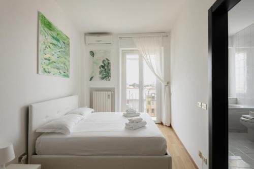 a white bedroom with a bed and a bathroom at Easylife - Elegante attico 2 min da Parco Sempione in Milan