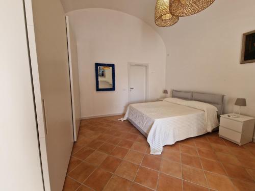 Casa Dei Nonni في ايسكيا: غرفة نوم بسرير أبيض وأرضية من البلاط