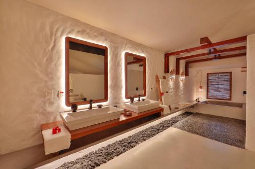 a bathroom with two sinks and two mirrors at Reserva Jacumã Boutique - Trancoso in Trancoso