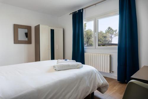 1 dormitorio con 1 cama con cortinas azules y ventana en Hotel Playa Las Sinas en Villanueva de Arosa