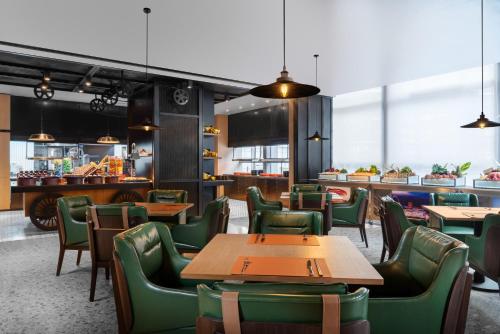 um restaurante com mesas de madeira e cadeiras verdes em Four Points by Sheraton Chongqing, Yongchuan em Yongchuan
