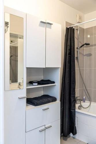 La salle de bains est pourvue d'une douche et d'une armoire blanche. dans l'établissement À Orly - Logement Moderne près de l'aéroport, à Orly