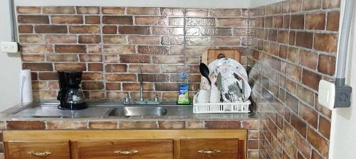 a kitchen counter with a sink and a brick wall at Apartamento AMUEBLADO in Canoas